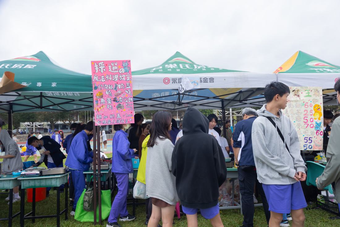 攤位張貼手繪海報，來賓在前方走動。