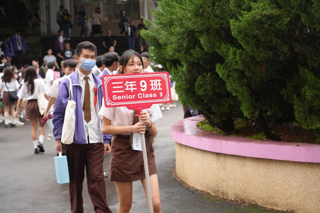 校園內學生手持寫著三年九班的班牌合影。