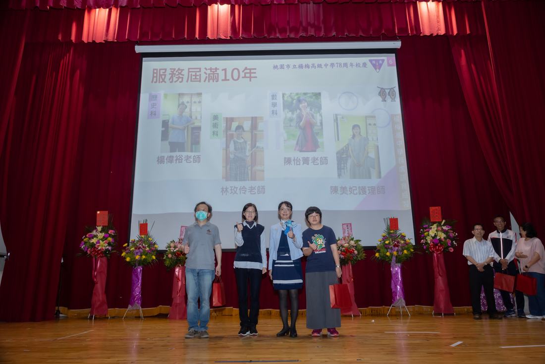 數位教師在舞台上受獎並持獎狀合影。