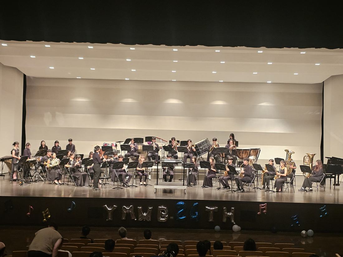 以較寬視角拍攝的舞台，樂團橫向排開演奏。
