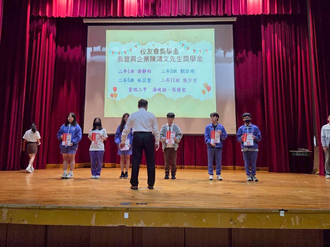 學生依序走上舞台等候頒獎，台下有人拍照記錄。