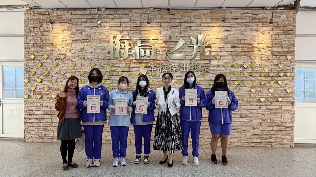 梅高之光牆前，學生手持獎狀面向鏡頭。