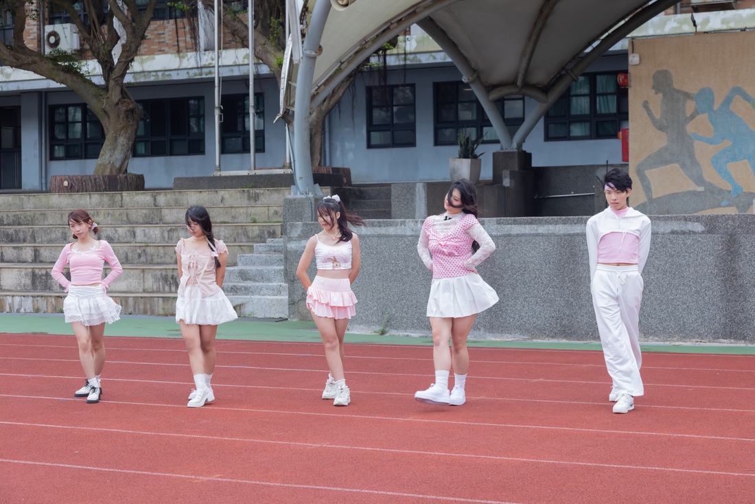 身著粉色服裝的學生在跑道上排成一列表演。