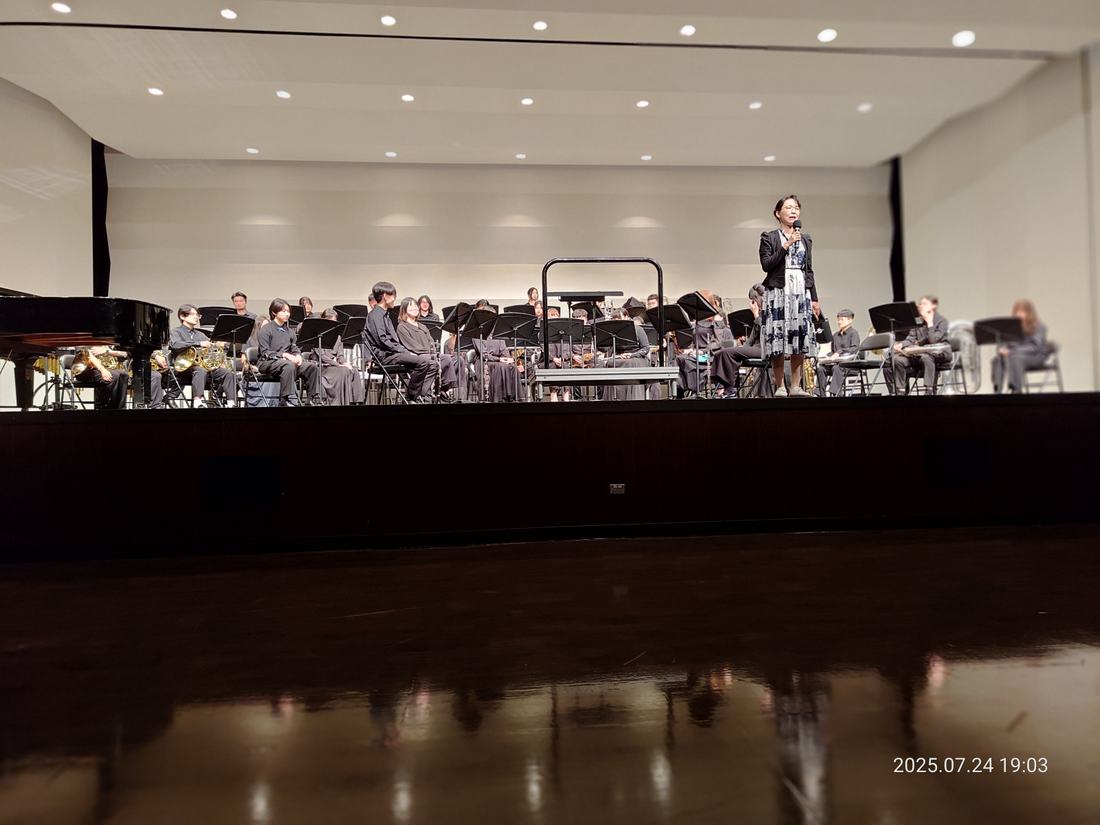 指揮立於指揮台上，樂團在後方演奏。