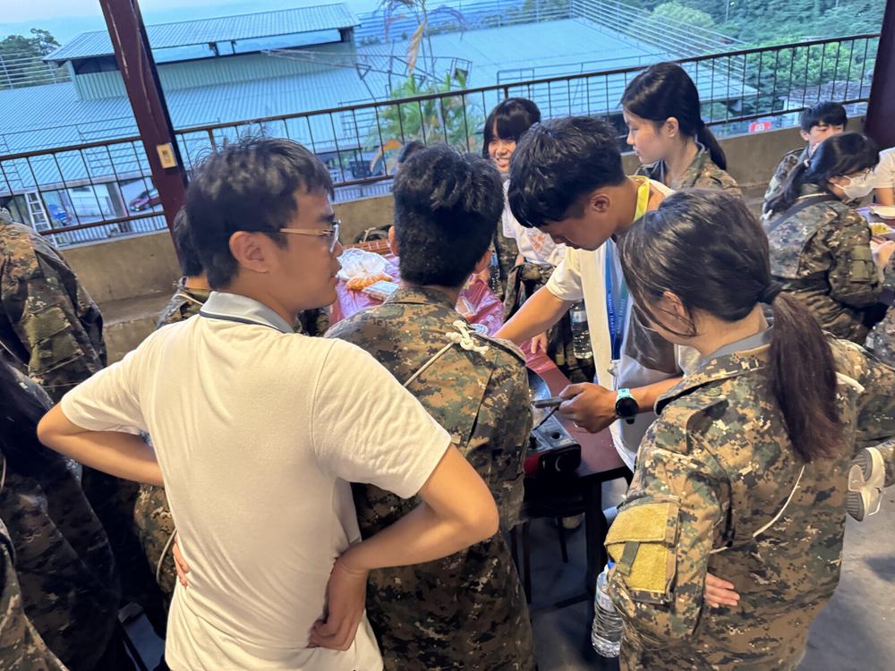 教官在戶外向圍攏的學員說明活動內容。