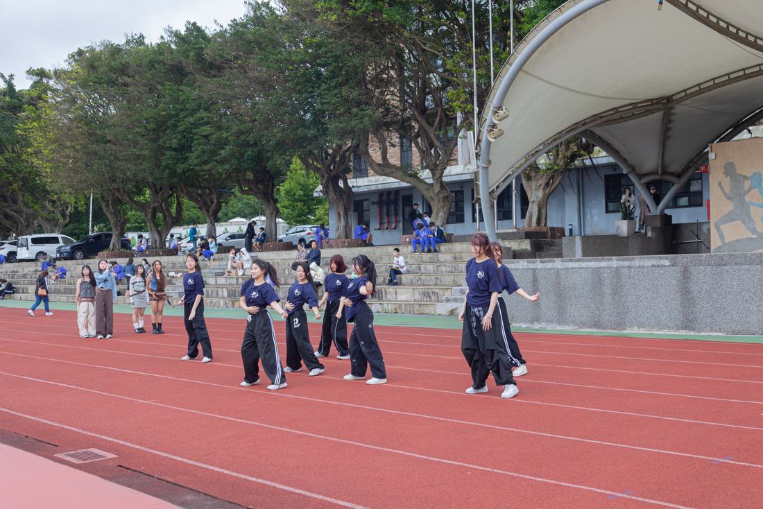 身著黑色服裝的學生在跑道上舞蹈演出。
