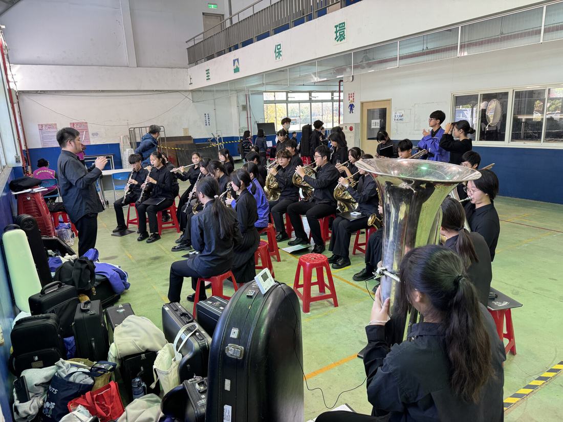 場邊堆放的樂器箱與器材，團員忙於搬運整備。