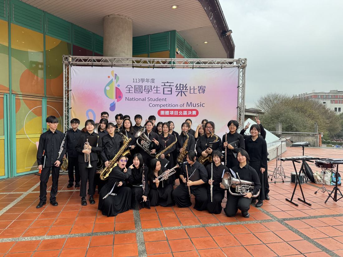全體團員在全國學生音樂比賽背板前手持樂器合影。
