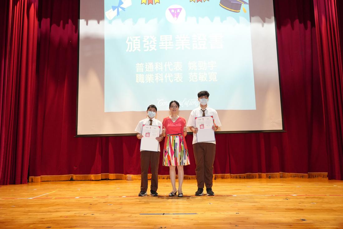 兩名學生代表站在舞台中央，投影幕顯示典禮資訊。
