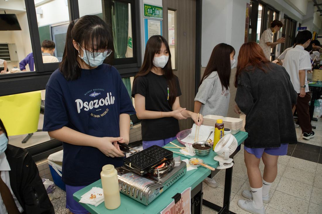 教室走廊上學生在攤位前排隊等候取餐。