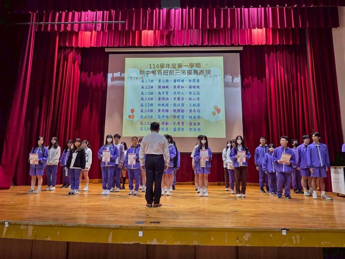 多名受獎學生橫向排成長列於舞台上合影。