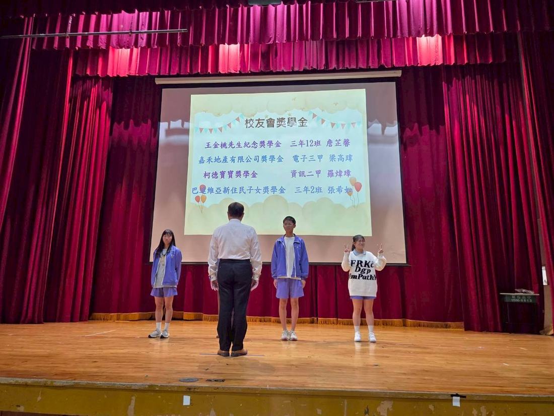 三名學生在舞台上接受頒獎並向觀眾致意。