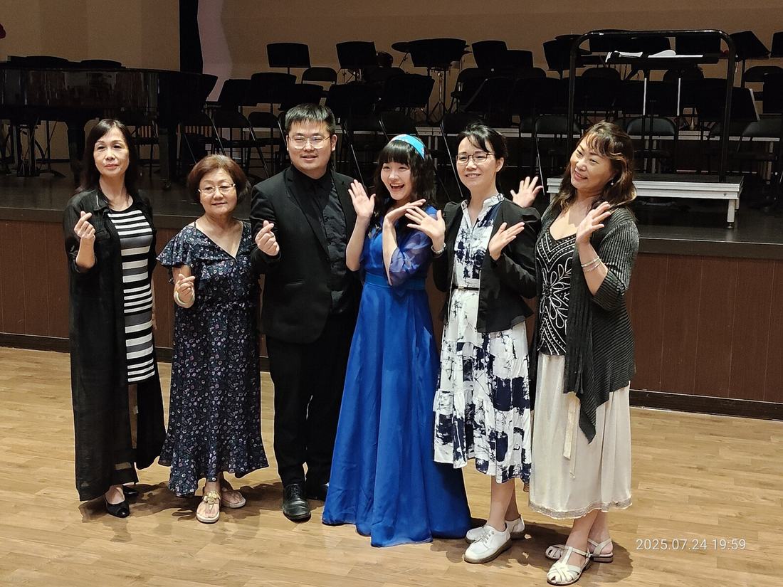 多位教師在舞台前並排合影，背景為演藝廳座位。