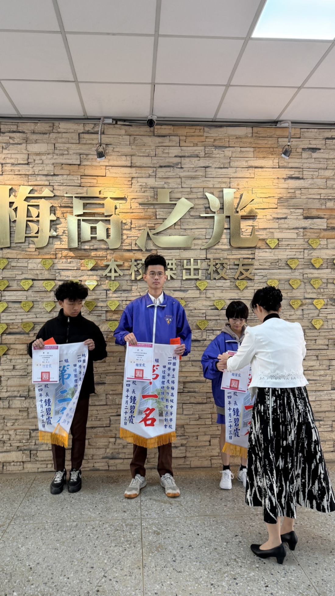 直式構圖，學生與教師在梅高之光牆前合影。